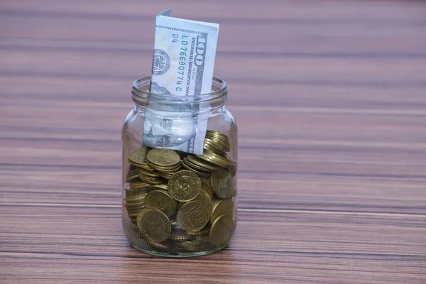 ビルは銀行に保存されているお金のシンボルとしてスティック アウトを 100 ドルからの硬貨の瓶 — ストック写真