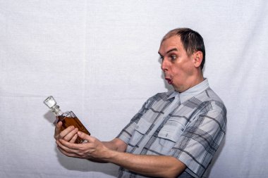 Bir adam elinde bir şişe alkol tutar ve çok sürpriz ona bakar.