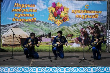 Ust-Kamenogorsk, Kazakistan - 22 Mart 2019: Ulusal kazak kostümleri genç müzisyenler dombra oynamak.