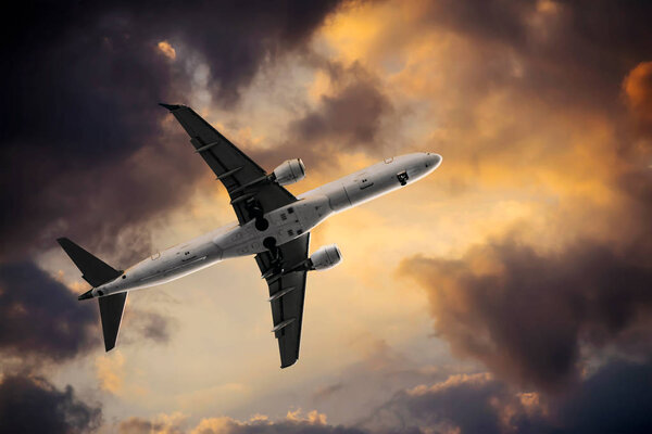 Passenger plane on the background of clouds filled with yellow light from the sun.