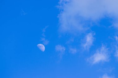 Bulutlar ile gündüz gökyüzünde yarım ay.