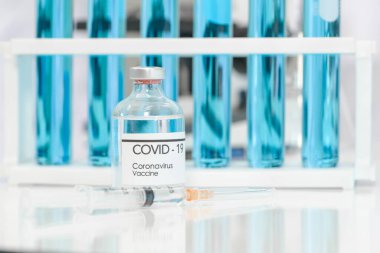 Bottle of coronavirus vaccine and syringe on white table. Science laboratory research and development concept.