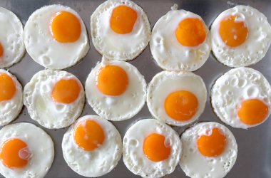 Sabah saatlerinde parlak bir mutfak ortamında pişirme tepsisinde sade bir şablona dizilmiş yumurta.