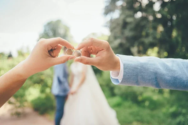 新婚夫婦とリング 背景にぼかしカップルと面白い結婚式の写真 — ストック写真