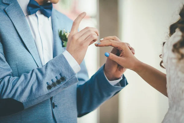 Um noivo elegante vestindo um anel no dedo de sua noiva elegante laço — Fotografia de Stock