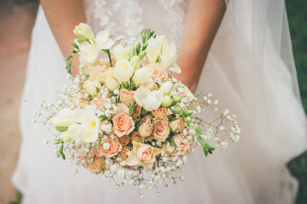 Женщина держит в руках красивый свадебный букет
