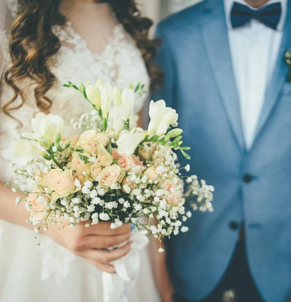 Bride and groom staying together with bouquet — Stock Photo, Image