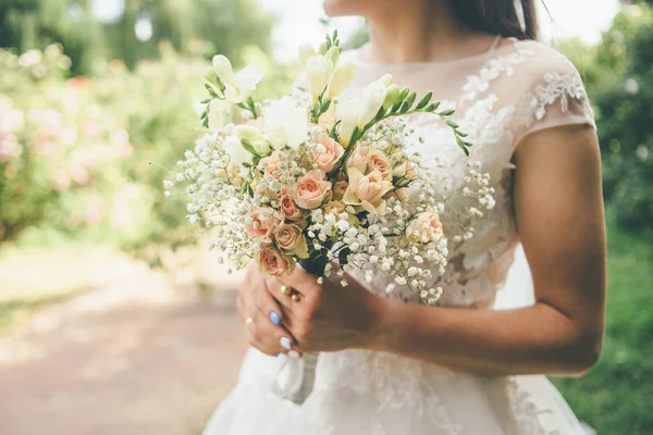 Novia en vestido de novia sosteniendo hermosas flores —  Fotos de Stock