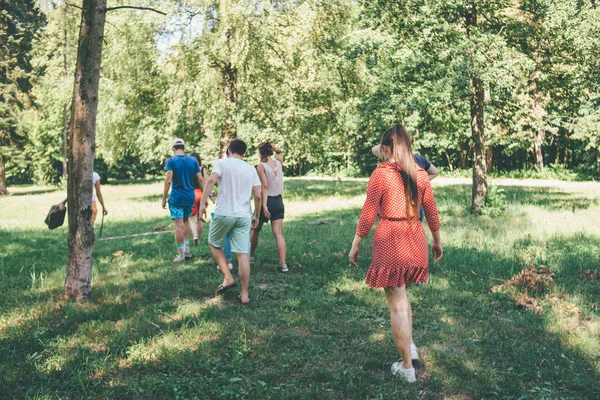 people are walking away together in the forest in sport wear