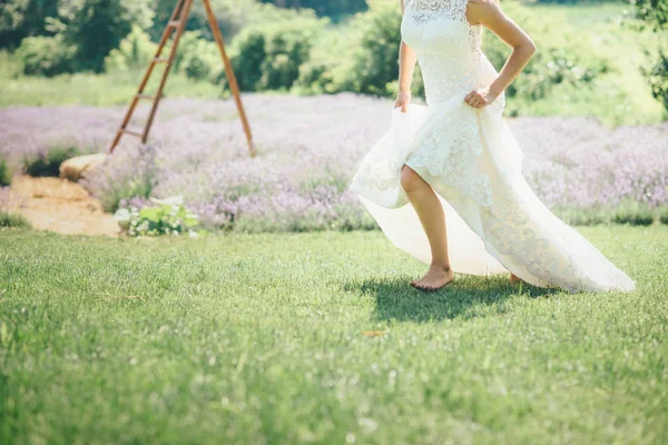 Kvinnan kör på gräset i brudklänning — Stockfoto
