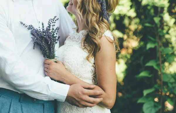 Hermosa pareja en vestido de novia blanco y pantalones azules se abraza en verano —  Fotos de Stock