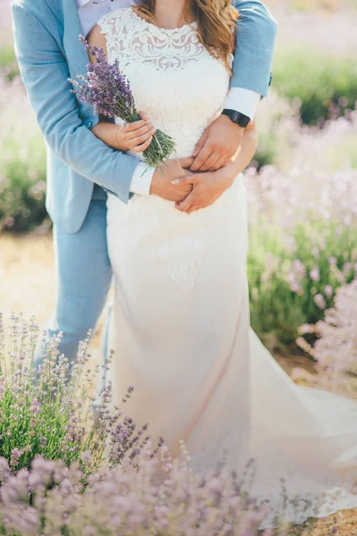 ブーケとラベンダー畑に抱いている結婚式のカップル — ストック写真