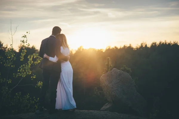 Casal casamento amoroso olhando para o pôr do sol — Fotografia de Stock