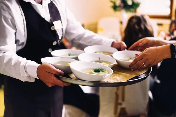 Waiter holds the tray with soups