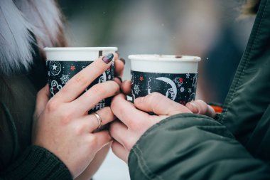 İki çift el onların kahve bardağı soğuk karlı havalarda, closeup fotoğraf tutun.