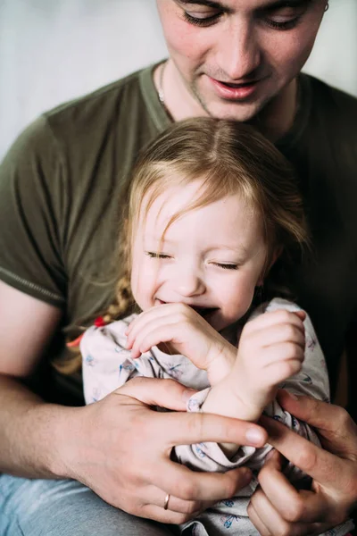 Blurred Young dad hugs his little baby child in his arms. He smiles and she laughs during the game. The relationship of the father with the child. Father\'s day