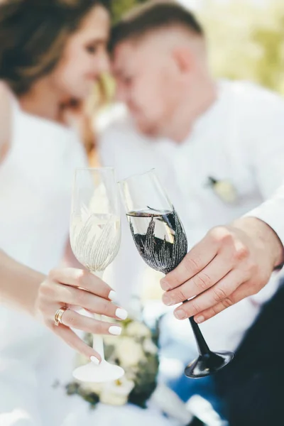 Närbild av ett glas i en svart och vit kant i händerna på en bröllopsdag. — Stockfoto