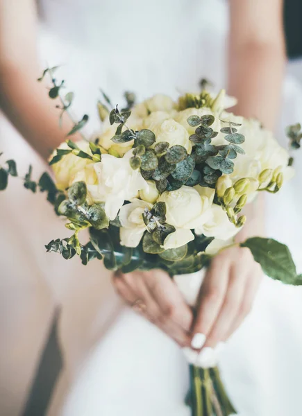 Κοντινό πλάνο ενός όμορφου νυφικού μπουκέτο στα χέρια της νύφης με λευκό φόρεμα. — Φωτογραφία Αρχείου