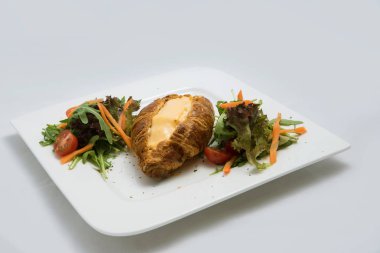 Sebze ile peynir dolu kruvasan ile bir kahvaltı tabağı düşük kontrast görüntü-havuç, domates, en az beyaz arka planda marul bir 30 derece açısı ile öne yakınlaştırılmış perspektif