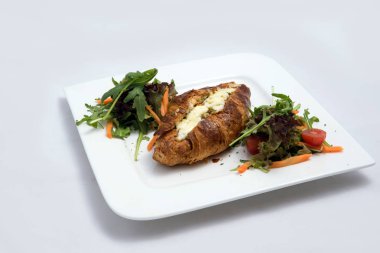 Peynir ve Zaatar ile kruvasan doldurulmuş bir kahvaltı tabağı bir düşük kontrast Hero çekim sebze ile kruvasanlar-havuç, domates, ön perspektiften 30 derecelik bir açı ile minimal Beyaz arka planda marul