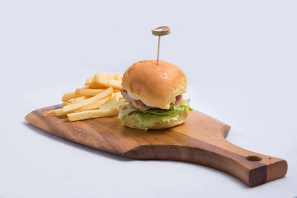 A low contrast Hero Shot of a grilled chicken slider burger, fries on a wooden platter board, on a minimal white background with a 45 degree angle from a diagonal perspective