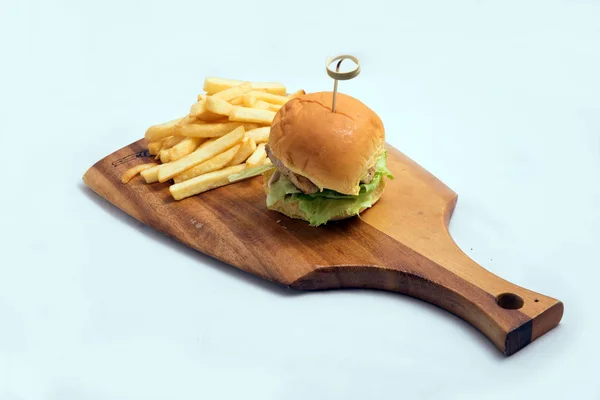 A low contrast Hero Shot of a grilled chicken slider burger, fries on a wooden platter board, on a minimal white background with a 45 degree angle from a diagonal perspective