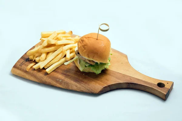 A low contrast Hero Shot of a grilled chicken slider burger, fries on a wooden platter board, on a minimal white background with a 45 degree angle from a diagonal perspective