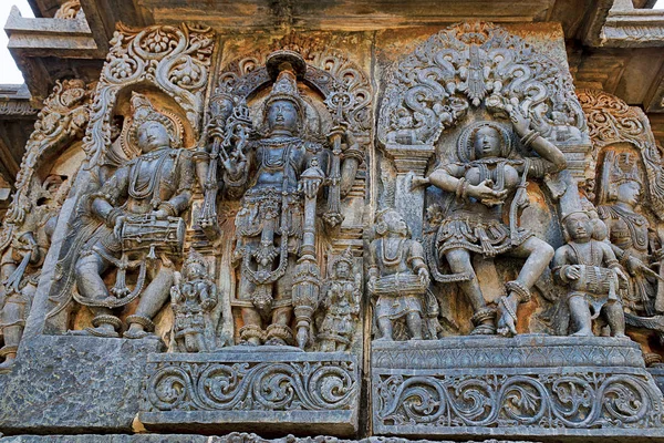 Rilievi ornati con pannelli murali raffiguranti la divinità sinistra che suona damaru, Vishnu e danza Sarswati, tempio di Hoysaleshwara, Halebidu, Karnataka — Foto Stock