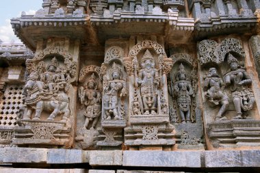 Shiva-Parvati solda, Brahma merkezi ve diğer tanrılar, Kuzey duvarı, Kedareshwara Tapınağı, Halebidu, Karnataka, Hindistan tasvir eden süslü duvar paneli kabartma.