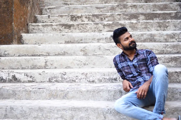 Male model sitting stairs looking up Sion fort, Mumbai — Stock Photo, Image