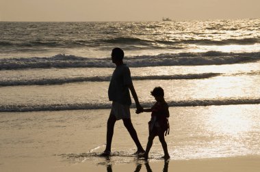 Dapoli, Maharashtra, Hindistan, Nisan 2012, turist yürümek sahilde günbatımı sırasında