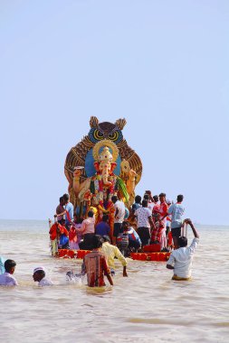 MUMBAI, MAHARASHTRA, September 2017, People carry Ganapati idol for immersion into the sea in wooden boats at Girgaum Chowpatty clipart