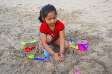 Küçük kız bir kale kum plajda Alibag, Konkan, Hindistan ile yapmaya çalışıyorum