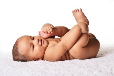 Ayaklarını tutarak ve gülüyor, Pune, Maharashtra yatakta uyuyan sevimli bebek