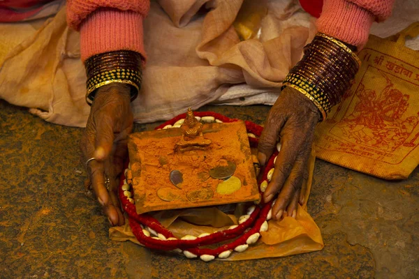 Woman with bangles and deity with saffron colored powder, Maharashtra, India.
