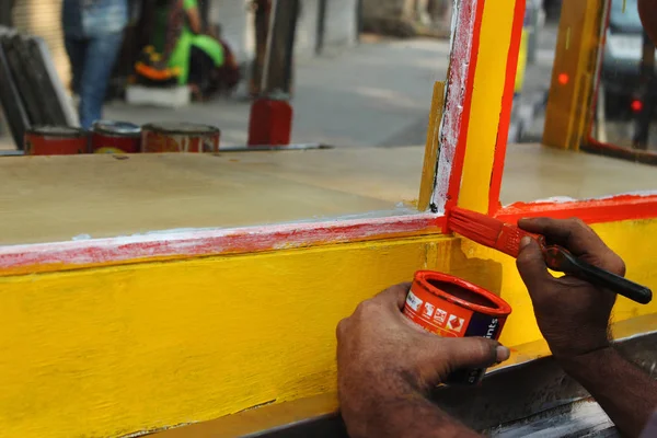 Mann bemalt Handwagen mit roter Farbe, Maharashtra, Indien. — Stockfoto