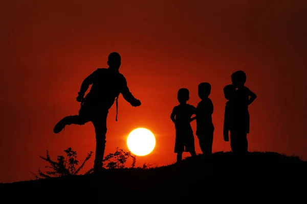 Силуэт мужчины с детьми, играющими с Солнцем, Махараштра, Индия . — стоковое фото