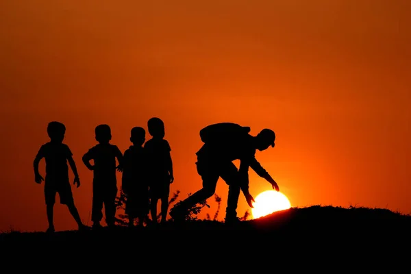 Silhuetten av man med barnen röra vid solen, Maharashtra, Indien. — Stockfoto