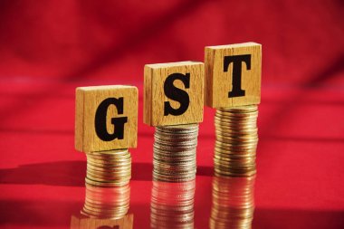 Ahşap harfler GST ve para sikke kırmızı masa arka plan üzerinde yığını, finansal konsept.