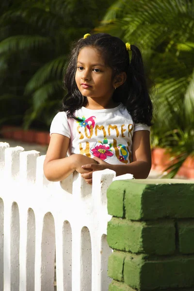 Chica india de pie en el parque descansando sus manos en la cerca del jardín, Pune . — Foto de Stock
