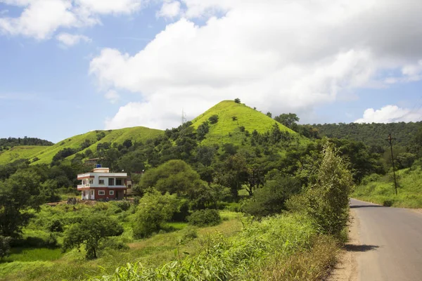 En naturskön utsikt med Bunglow, frodig grön kulle och väg under Monsoon, Mandvi Khurd, Pune distrikt. — Stockfoto