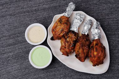Keskin baharat ve yoğurt salamurasıyla yapılmış tavuk tandırı bacakları ve tandoda veya fırında pişirilmiş.