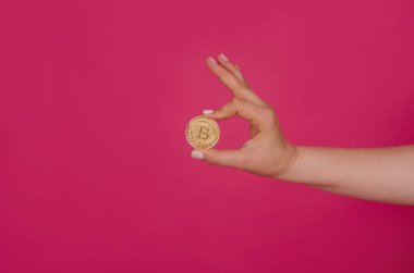 Cryptocurrency altın bitcoin sikke pembe bir arka plan üzerinde. Kripto para - bankacılık web ve uluslararası ağ ödeme için elektronik sanal para biriminin simgesi tutan el