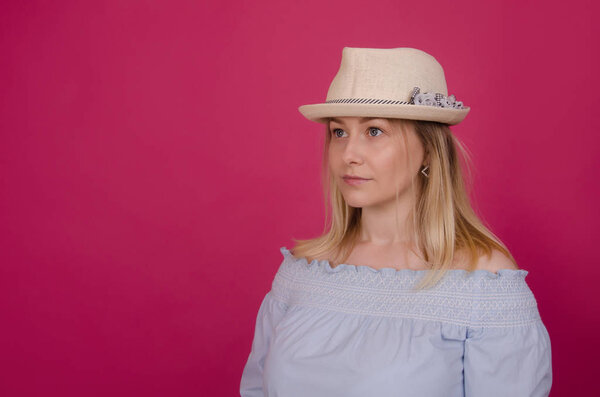 Portrait of beautiful woman in straw hat and blue dress. Clean face with good skin. Stylish woman in casual clothes. Isolated on pink studio background. Summer holidays, recreation and vacation concept.