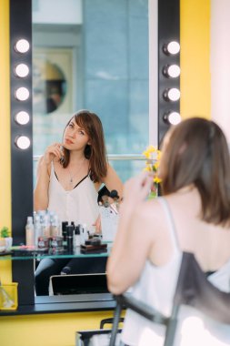 Çekici sarışın kız taranmak ayna güzellik stüdyosu lambalar ile. 