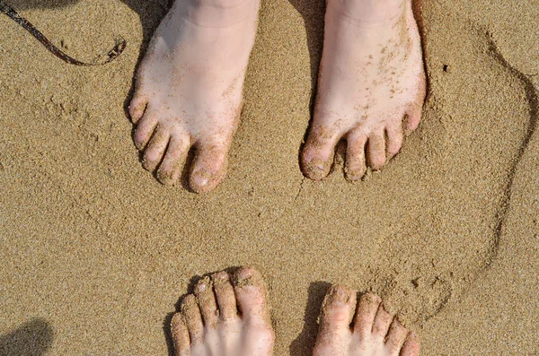 Man and woman feet on sand on beach. Top view of legs on sandy beach. Summer, holidays background, vacation concept