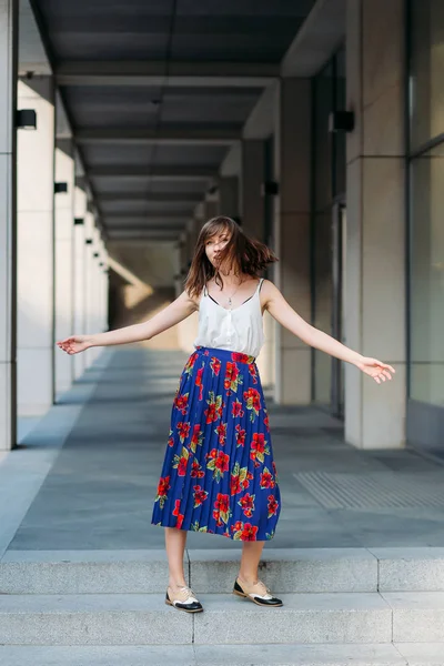 Stylish woman dancing in the street.Woman portrait indoors. Fashion lifestyle portrait of pretty woman. Woman portrait outdoors in floral skirt and white top.