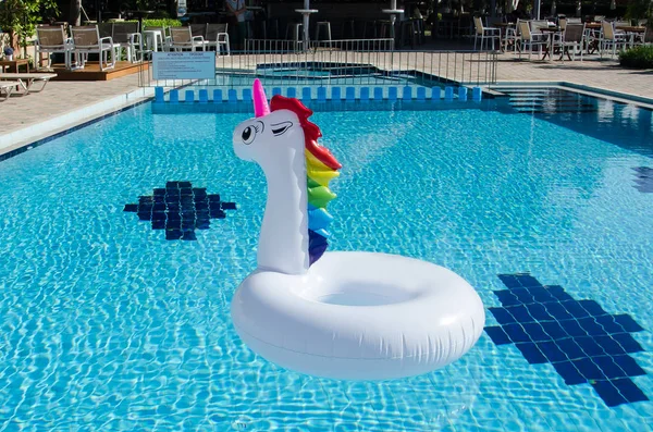 Unicorn pool float in blue water background, inflatable swim tub