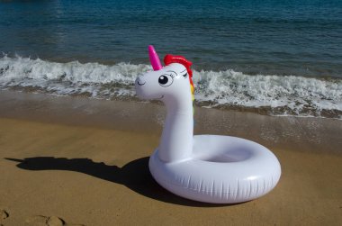 Şişme unicorn kum deniz kenarında üzerinde. Yaz tatili, tatil plaj. 