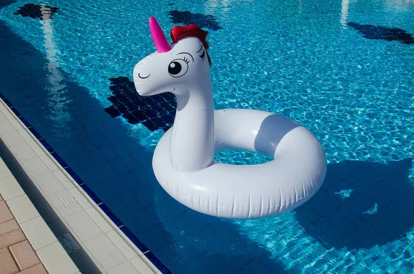 Inflatable unicorn pool toy floating in swimming pool. Unicorn inflatable pool float